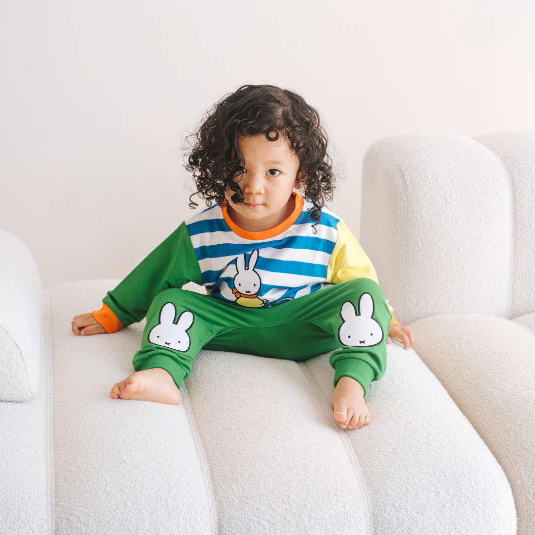 Child wearing the Miffy on the Move bamboo lounge set with bicycle sweatshirt and green joggers